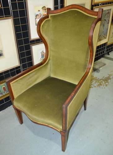 An early 20th Century wing armchair with exposed crossbanded mahogany frame, upholstered in green draylon above square tapered legs.