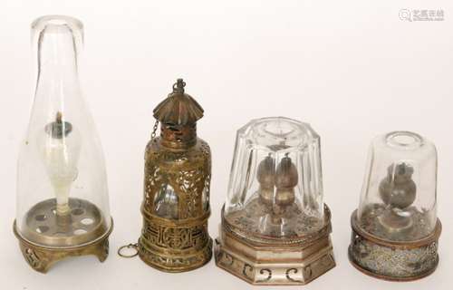 A Chinese travelling brass opium lamp with internal glass cover within a pieced case, height 19cm, together with two faceted glass covered lamps and another of waisted conical form (4)