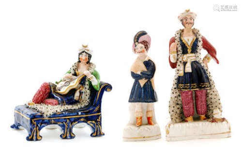 Three 19th Century Staffordshire theatrical figures each modelled as a male in Turkish dress, the first stood with his arms folded with a blue feather in his cap, the second stood wearing a crimson coat with encrusted ermine trim and the third reclining on a chaise longue playing the loot, all unmarked (3)