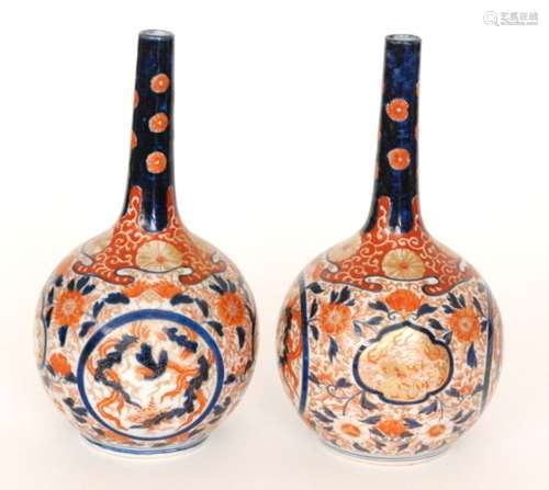 A pair of early 20th Century Japanese export Imari vases of globe and shaft form each decorated with a stylised bird within a roundel against a patterned ground, each with a painted tree mark to the base, height 26cm