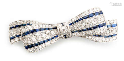 An Art Deco platinum sapphire and diamond bow brooch, the ribbon tied bow set with two rows of calibre cut sapphires beside scrolling millegrain set old European diamonds, central diamond in a rub over setting with further calibre set sapphire highlights, length 7cm, unmarked.