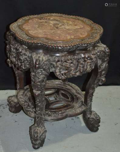 A late 19th to early 20th Century Oriental Export hardwood jardiniere stand with a rouge marble inset top within a foliate relief carved border, raised to four legs carved with dragon detail with a conforming apron and stretcher shelf, height 53.5cm, S/D.