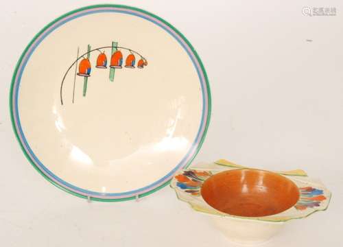 A Clarice Cliff Wilkinson Daffodil shape grapefruit dish decorated in the hand painted Crocus pattern with sprays of flowers between yellow and green banding with a brown well, printed mark, length 17.2cm, together with a Clarice Cliff Newport plate decorated in the Solomon's Seal pattern, printed Bizarre mark, diameter 23cm. (2)