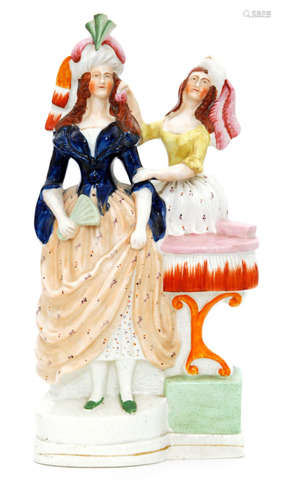 A 19th Century Staffordshire figure modelled as a lady stood holding a fan and dressed in a cobalt blue bodice and patterned skirt with her attendant by her side placing a pink flower in her hair and stood before a small table, unmarked, height 32cm