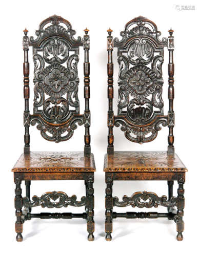 A pair of 19th Century Carolean style carved oak high back hall chairs with plank seats on turned legs united by scroll stretchers (2)