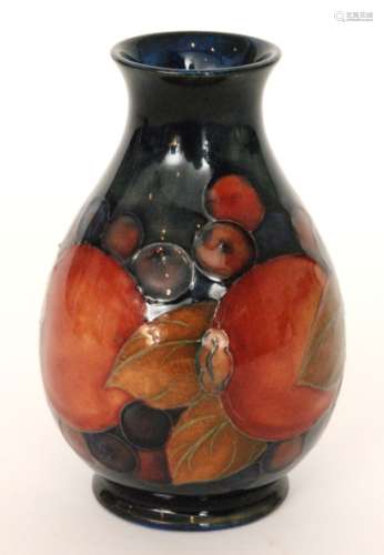 An early 20th Century Moorcroft baluster vase decorated in the Pomegranate pattern with a band of whole fruit and berries against a blue wash ground, impressed mark, monogrammed in blue, height 12cm