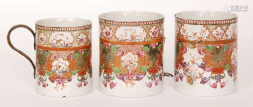 A Chinese Qing Dynasty Qianlong period 18th Century famille rose mug, hand painted with cartouche panels of exotic birds over an ornate scroll work ground with gilded high lights, height 14cm, together with two further examples, all A/F. (3)  BR - 1999/118