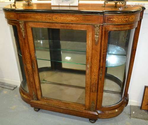 A late 19th Century marquetry inlaid bowfronted credenza enclosed by glazed doors with gilt metal mounts below an ebonised cornice on a platform base, width 124cm