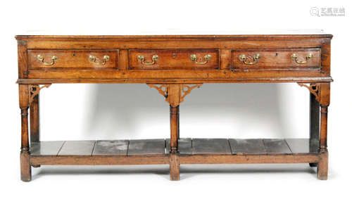 An early 19th Century oak and mahogany crossbanded three drawer dresser, brass drop handles on turned legs united by a pot board, length 184cm