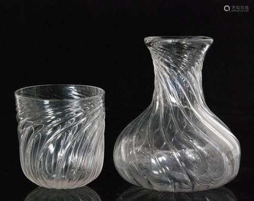 An early 20th Century Stevens & Williams clear crystal glass water jug designed by Gordon Russell of compressed globe and shaft form with wrythen decoration, height 14cm, together with a matched tumbler, height 9cm. (2)