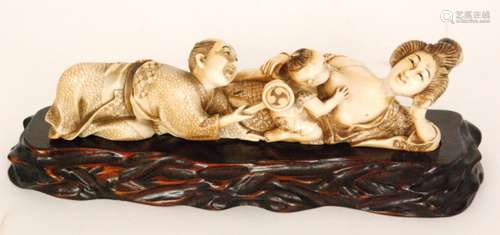 A late 19th Century Japanese carved ivory figure group of a suckling child with parents, bears signature, on a carved hardwood stand, length 21cm, S/D.