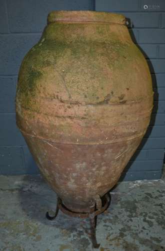 A 19th Century terracotta Romanesque oil storage jar of conical form on a cast iron stand, height 89cm