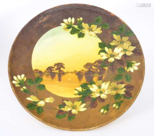 A large Burmantofts Faience impasto decorated charger with an off centre roundel depicting a sunset tree lined landscape with a brown border edge with thickly applied white prunus blossom and foliage, impressed mark, diameter 42.5cm