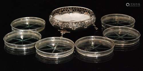 A hallmarked silver pierced circular dish raised on three claw and ball feet, Birmingham 1930, Adie Brothers Ltd, and a set of six Sterling silver mounted circular glass coasters each with shallow pierced gallery (7)