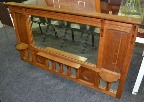 An early 20th Century Arts and Crafts oak overmantle mirror, the cornice top above a pair of corbel brackets flanking a central shelf, height 87cm and width 155cm.