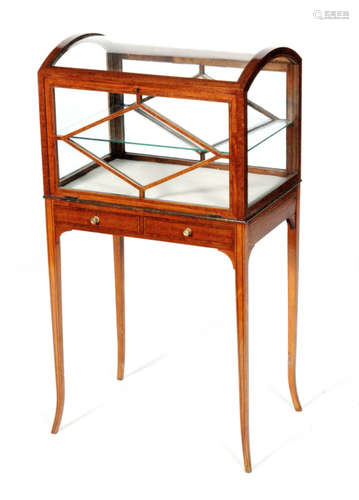 An early 20th Century satinwood vitrine or bijouterie cabinet of casket form, with a hinged fall front panel above two small frieze drawers and raised to square tapered legs, lacking cross-stretcher, height 91cm and width 48cm.