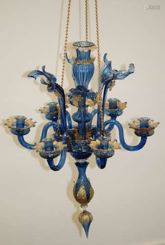 A late 19th to early 20th Century Venetian glass six light chandelier in the manner of Salviati, the central knopped column separated with a platform supporting six scroll arms with cup sconces between six straight arms with hot worked leaf decoration, all in a pale blue ground with moulded decoration with applied decoration with gold aventurine highlights, columns height 65cm.