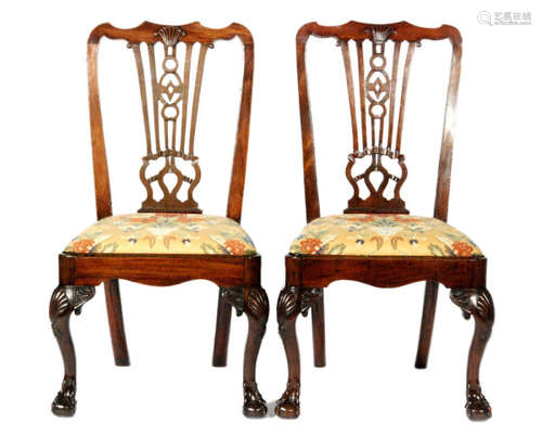 A pair of mahogany standard chairs in the Chippendale style, with pierced splats above drop-in seat pads, the front legs with shell and acanthus carved knees and claw and ball feet, some later repairs, S/D. (2)