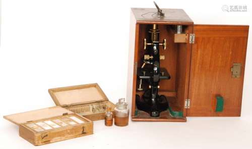 An early 20th Century brass and black laquered microscope in fitted mahogany case with spare lens together with a collection of botany slides some labelled E Wheeler London (2)