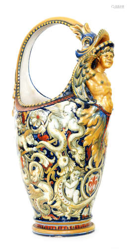 A large early 20th Century Cantagalli pedestal basket vase decorated in the Renaissance style with cherubs, stylised birds and grotesque griffin in tones of green with copper lustre detailing against a blue ground, the handle formed as a fish with its head leaning upon a male torso with wings, bears paper label stating 'The gift of her Majesty Queen Victoria to Susan, Duchess of Roxburghe', the cockerel beneath the label, height 51cm