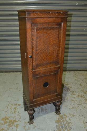 A 1930s oak humidor cabinet enclosed by a panelled door on carved legs on hoof feet, width 34cm