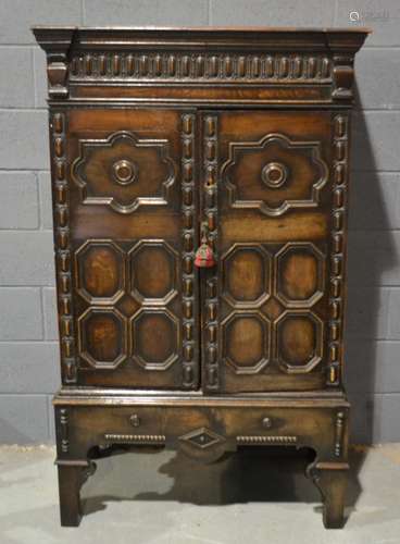 An oak double door cupboard with moulded cornice above stylised bracket feet, height 165cm and width 99cm.