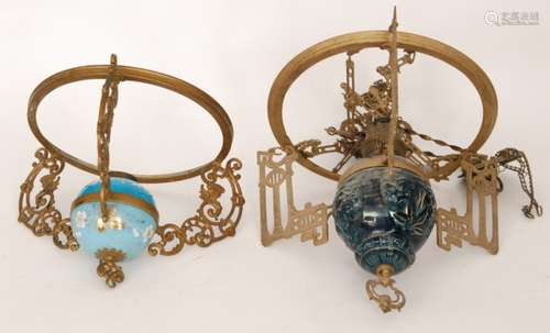 An early 20th Century pressed gilt metal ceiling light fitting with blue reservoir and applied decoration with white opaque shade and a similar lamp (2)