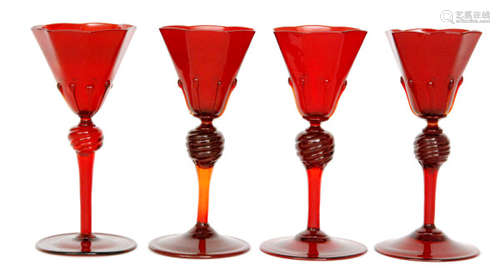 A set of four early 20th Century Salviati wine glasses the spread foot below the drawn stem to a wrythen knop below the octagonal flared bowl with applied tear trails to the base all to the deep ruby ground, unmarked, height 14cm.