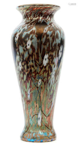 A Okra studio glass vase of tapered form below a flare neck decorated with stylised flower heads and green mottling over the pale brown ground ground all picked out in iridescence, acid marked, height 22cm.