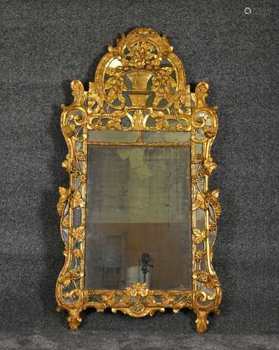 Miroir de Cheminée. Large fronton sculpté d'une grande corbeille de fruits. Encadrement à parcloses entièrement parcouru par des pampres de vignes. Bois doré. Travail d'époque Régence du Sud de la France - Provence. Dimensions: 205 x 110 cm.