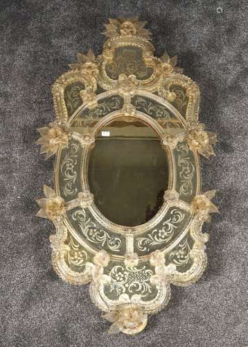 Miroir de Venise. De forme violonée et entièrement rehaussé de fleurs. Baguettes torsadées. Verre gravé d'enroulements. Dimensions: 135 x 70 cm.