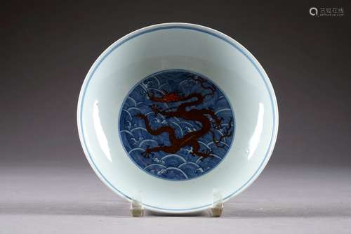 Coupe sur Pied talon. Ornée, au centre d'un médaillon figurant un dragon à cinq griffes entouré de flots stylisés et présentant, sur le pourtour, un décor similaire. Porcelaine de Chine à émail rouge de fer et bleu. Marque sigillaire de Kien-Long. Diamètre: 17,5 cm. Condition: Pas d'accident ni de restauration.