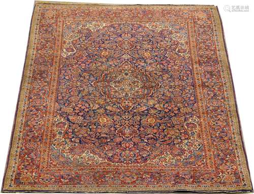 Carpette Kashan. Le fond bleu nuit est décoré, en plein, de fleurettes. Ecoinçons découpés à fond blanc. Bordure ton sur ton. Dimensions: 203 x 133 cm.