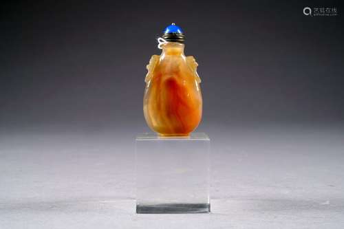 Tabatière. flanquée de deux petites anses simulant des anneaux retenus par une tête de Chimère. Agate sculptée. Chine. Hauteur: 8 cm.