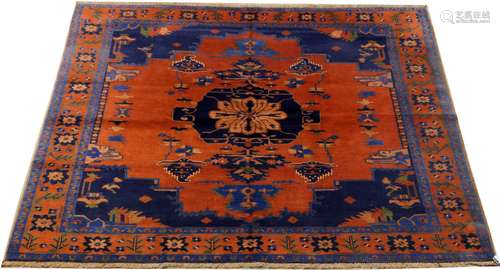 Tapis d'Orient. Fond rouge à larges écoinçons bleus. Bordure ornée de fleurons. Dimensions: 214 x 127 cm.