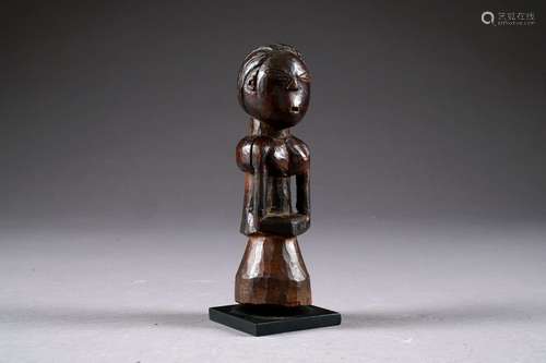 Figure d'Ancêtre Kusu de Forme schématisée. Au bassin évasé, les mains posées sur l'abdomen. Bois sculpté à patine sombre. République démocratique du Congo. Hauteur: 17,5 cm.