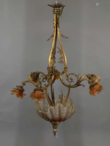 Lustre “Belle Epoque“. Monture mouvementée en bronze doré, à têtes de bélier, retenant six tulipes et trois coquilles de verre de couleur moulé pressé. Vers 1900. Hauteur: 105 cm.