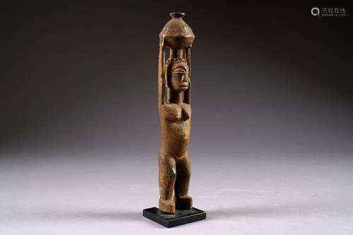 Lobi. Statuette figurant une femme debout portant un récipient sur la tête soutenu par les deux bras. Bois sculpté et patiné. Burkina Faso. Hauteur: 30 cm.