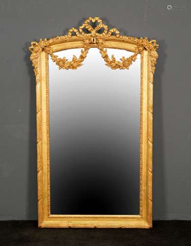 Miroir de Style Louis XV. Sommé d'un large ruban noué retenant une guirlande de fleurs. Encadrement mouluré. Bois doré. Dimensions: 146 x 87 cm.