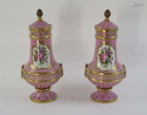Paire de cassolettes en porcelaine à décor de bouquets de fleurs sur fond rose et or, les prises en bronze.