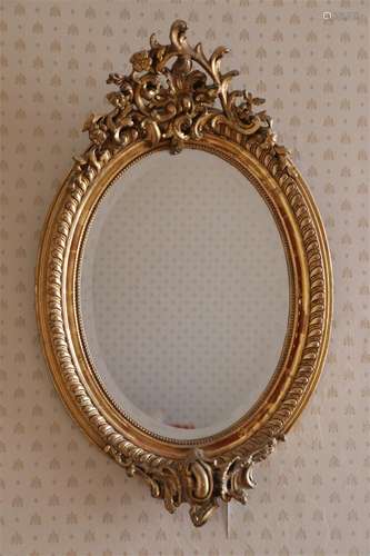 Miroir ovale en bois doré de forme rocaille.