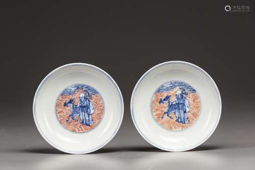 A pair of Chinese iron-red-decorated blue and white 'Immortals' saucers