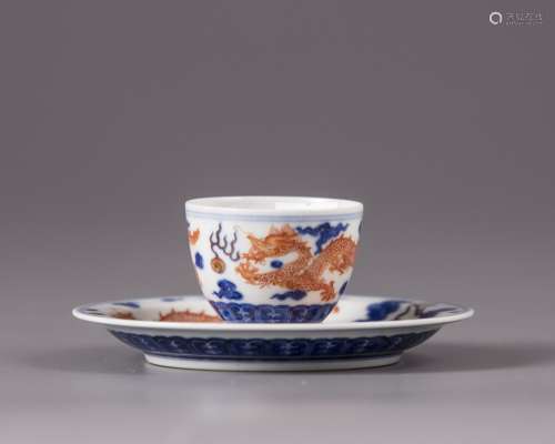 A small Chinese iron-red-decorated blue and white 'dragon' cup and saucer