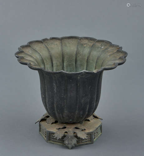A green bronze vessel in the shape of a flower calyx