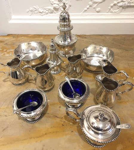 ENSEMBLE en argent anglais uni aux initiales entrelacées MC comprenant :  2 coupelles 5 pots à crème paire de salerons 1 saupoudoir 1 salière 1 moutardier Orfévre Goldsmiths & Silversmiths Co Poids total : 1850 g Vers 1920  Provenance : la cantatrice Marthe Chenal (1881-1947), Soprano notamment à l'opéra Garnier entre 1905 et 1923.