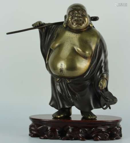 Japanese bronze figure of Hotei the god is shown standing holding a staff over his shoulder supporting a large bag on his back, fan in other hand, Signed at the base of bag