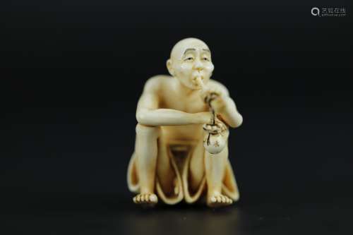 Vintage Netsuke carving of a man smoking while showing his genital