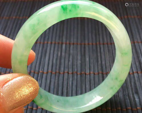 A NATURAL JADEITE OVAL SHAPED BANGLE