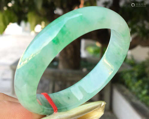 A NATURAL JADEITE OVAL SHAPED BANGLE