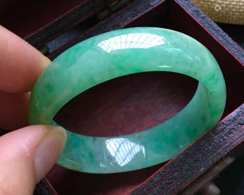 A NATURAL JADEITE OVAL SHAPED BANGLE